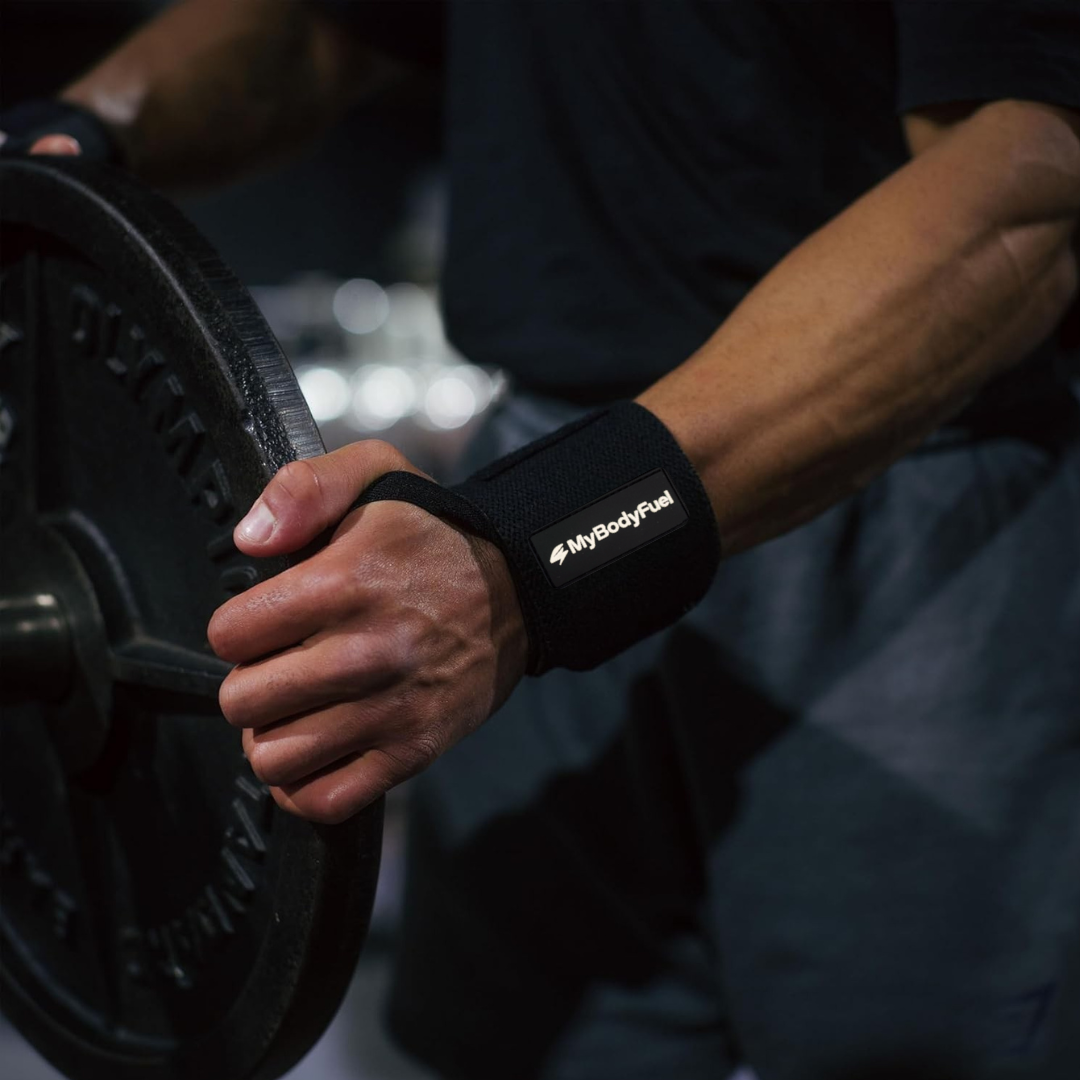 Man gebruikt MyBodyFuel wrist wraps tijdens krachttraining met halterschijf – zwarte polsbanden voor extra grip en polssteun.
