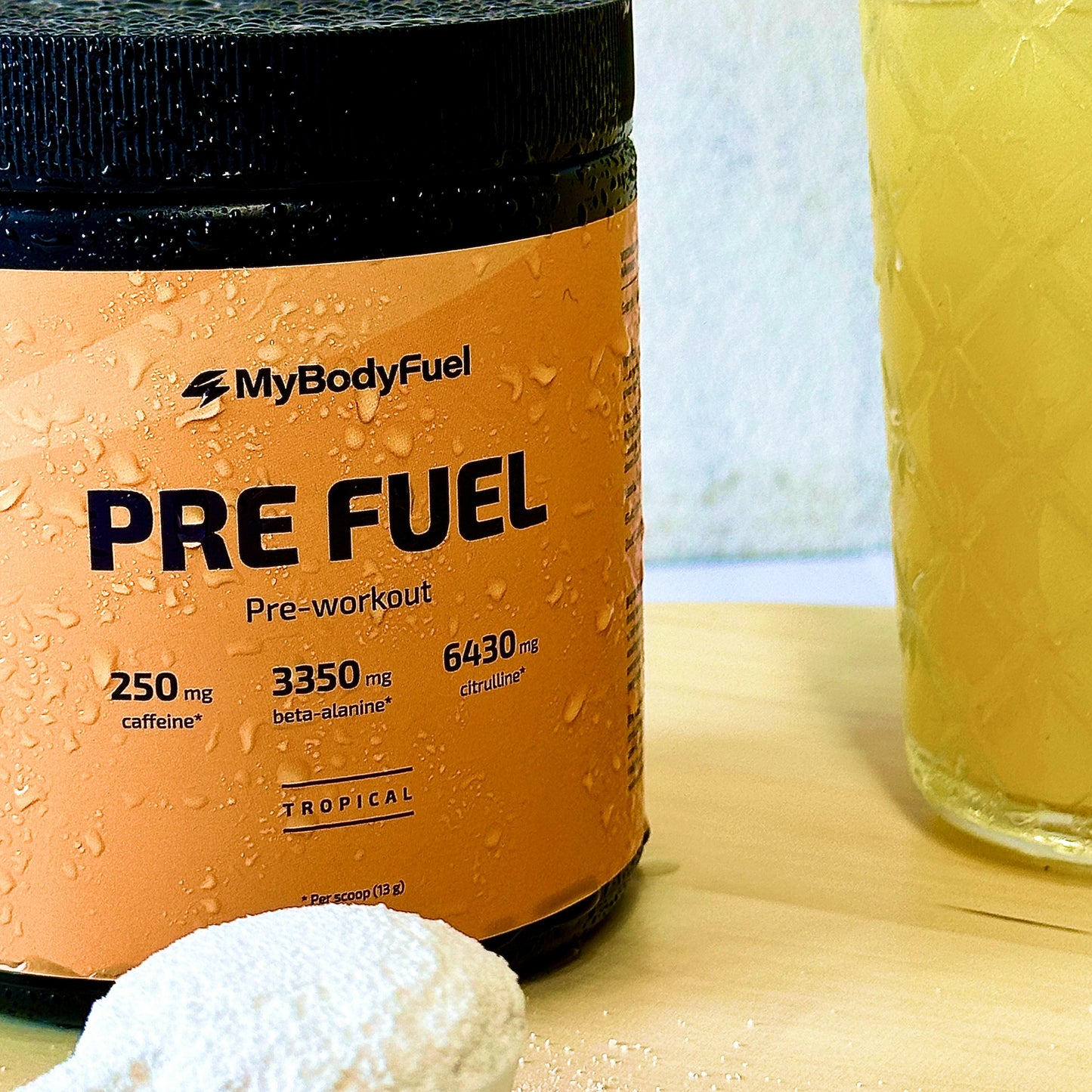 Scoop tropical Pre Fuel poeder naast MyBodyFuel pot en shakebeker – klaar om te mixen