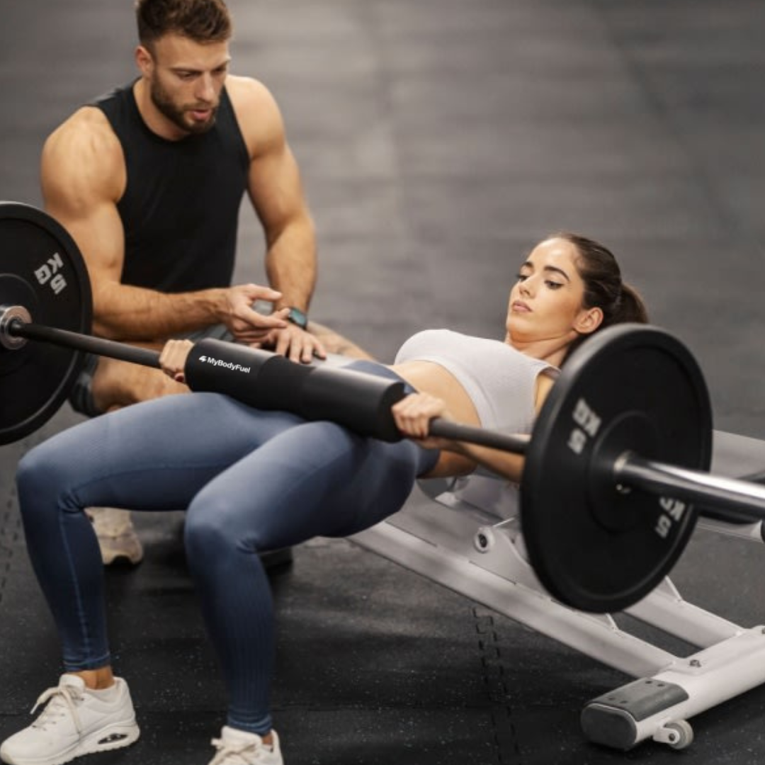 Vrouw traint hip thrust met zwarte barbell pad – MyBodyFuel hip thrust kussen